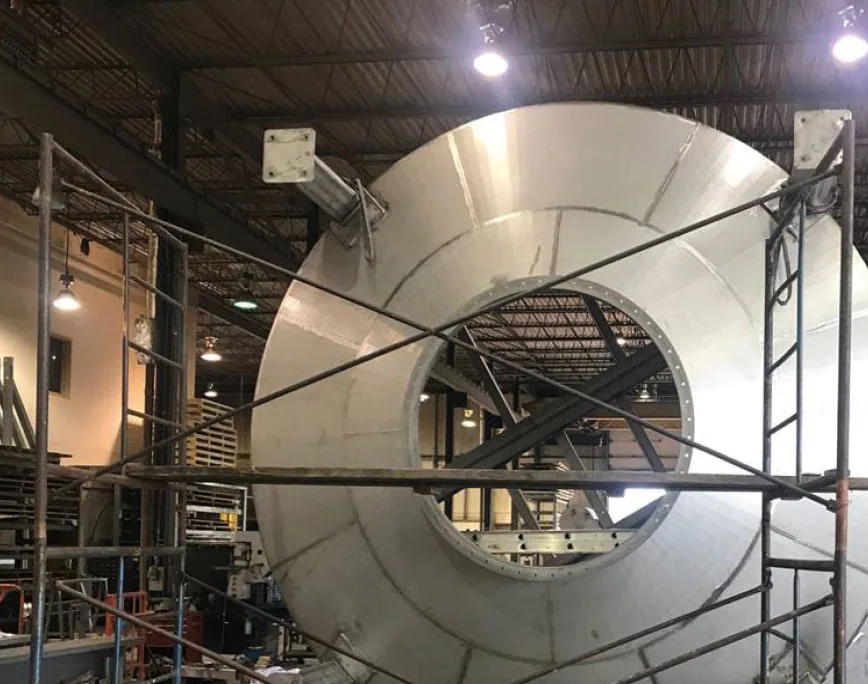 Large circular stainless steel structure in fabrication inside the ADI Laval shop