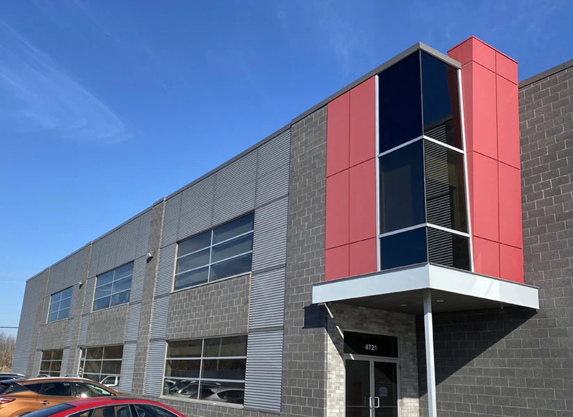 Devanture de l'atelier ADI Laval à Laval, Québec — bâtiment industriel moderne, béton, métal ondulé et panneaux rouges, entrée 4721.