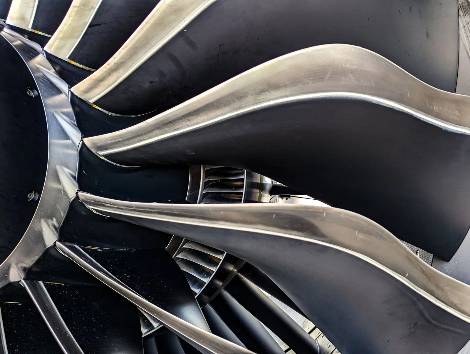 Close-up of the metal fan blades of a jet engine, illustrating the precision required in aerospace fabrication.