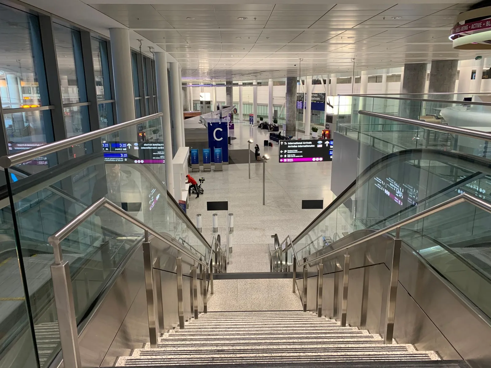 Garde-corps en acier inoxydable sur mesure le long d'un escalier commercial en verre et métal dans un hall moderne
