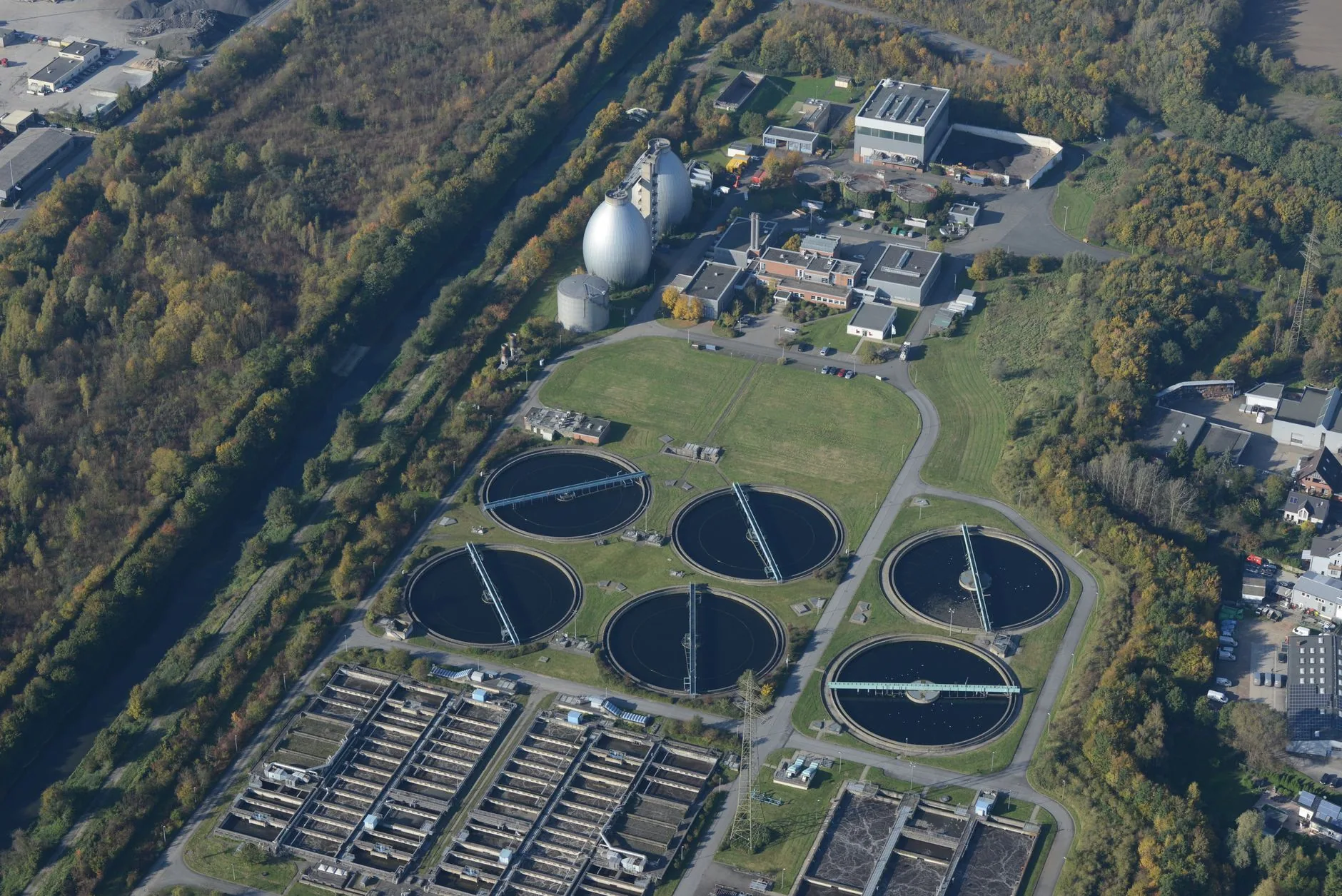Vue aérienne d'une station d'épuration avec plusieurs bassins circulaires de décantation.