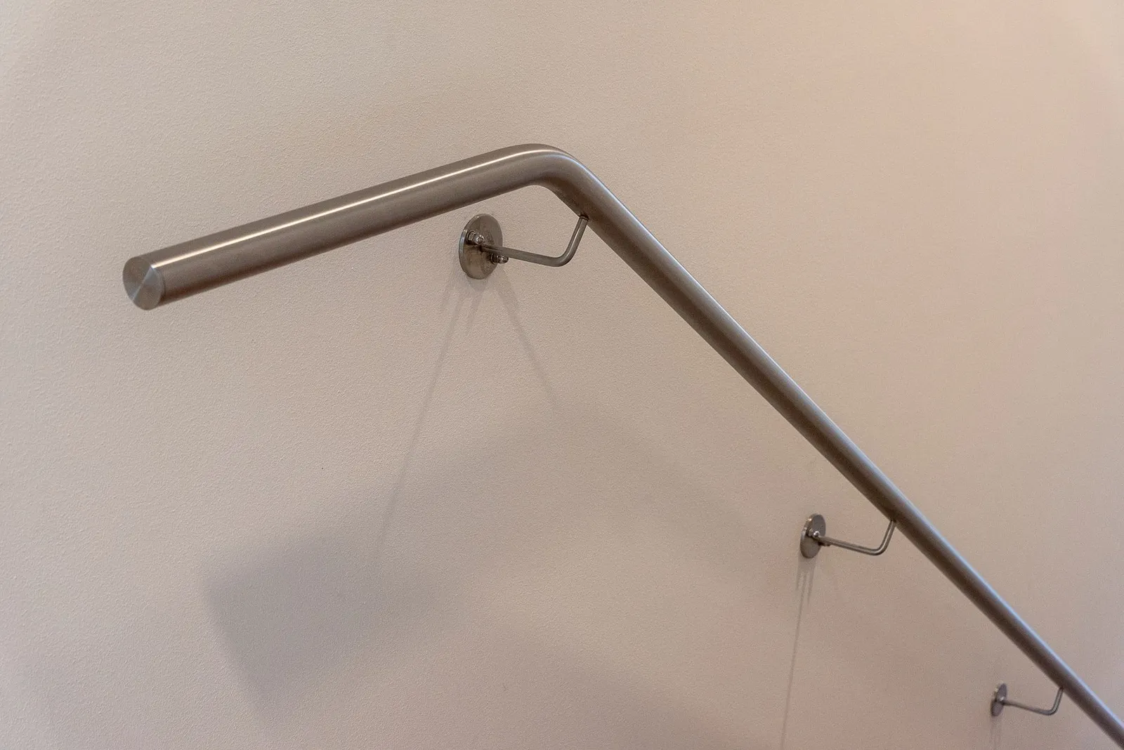 Main courante en inox poli fixée au mur d'un hall institutionnel contemporain