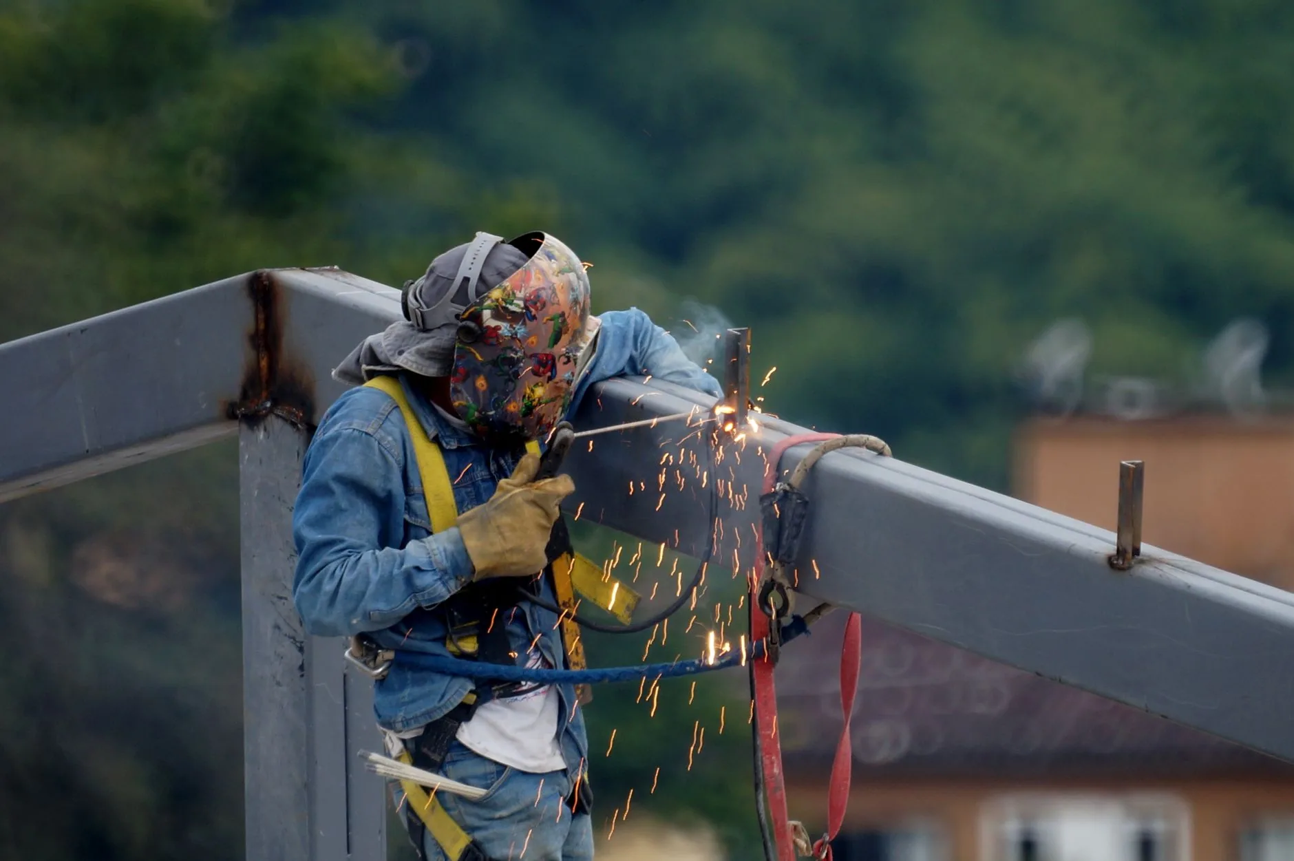 Soudeur à l’arc assemblant une grande structure métallique sur un chantier.